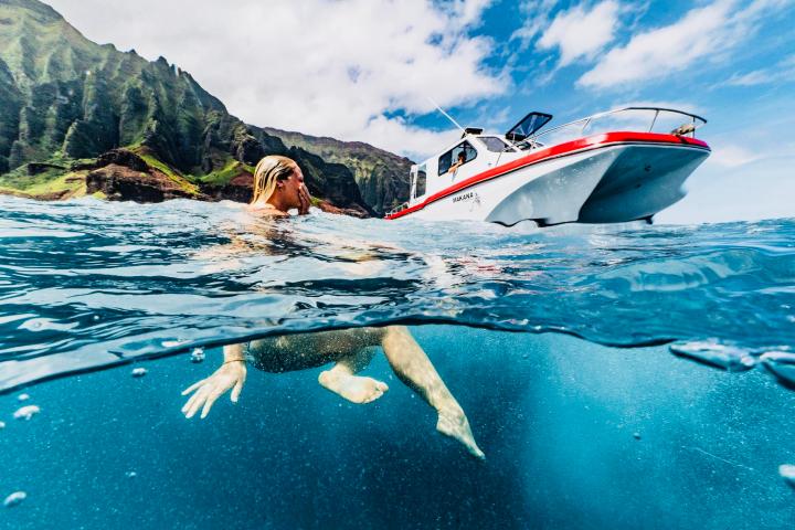 a dog swimming in a body of water with a mountain in the background